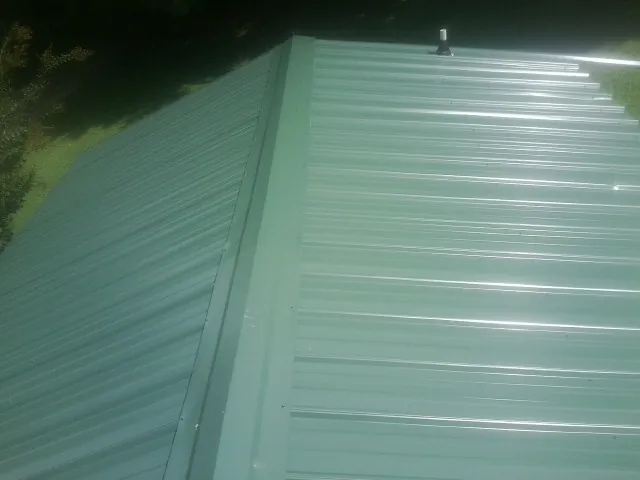 New green metal panels meeting at the ridge of a roof — Flat Roof Repair work by our crew in Palmetto