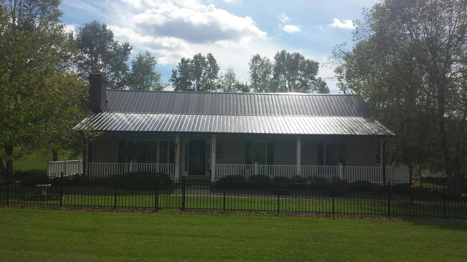 Gray metal roof on a brick ranch with a full width front porch — Gutter Guard Installation work by our crew in Palmetto