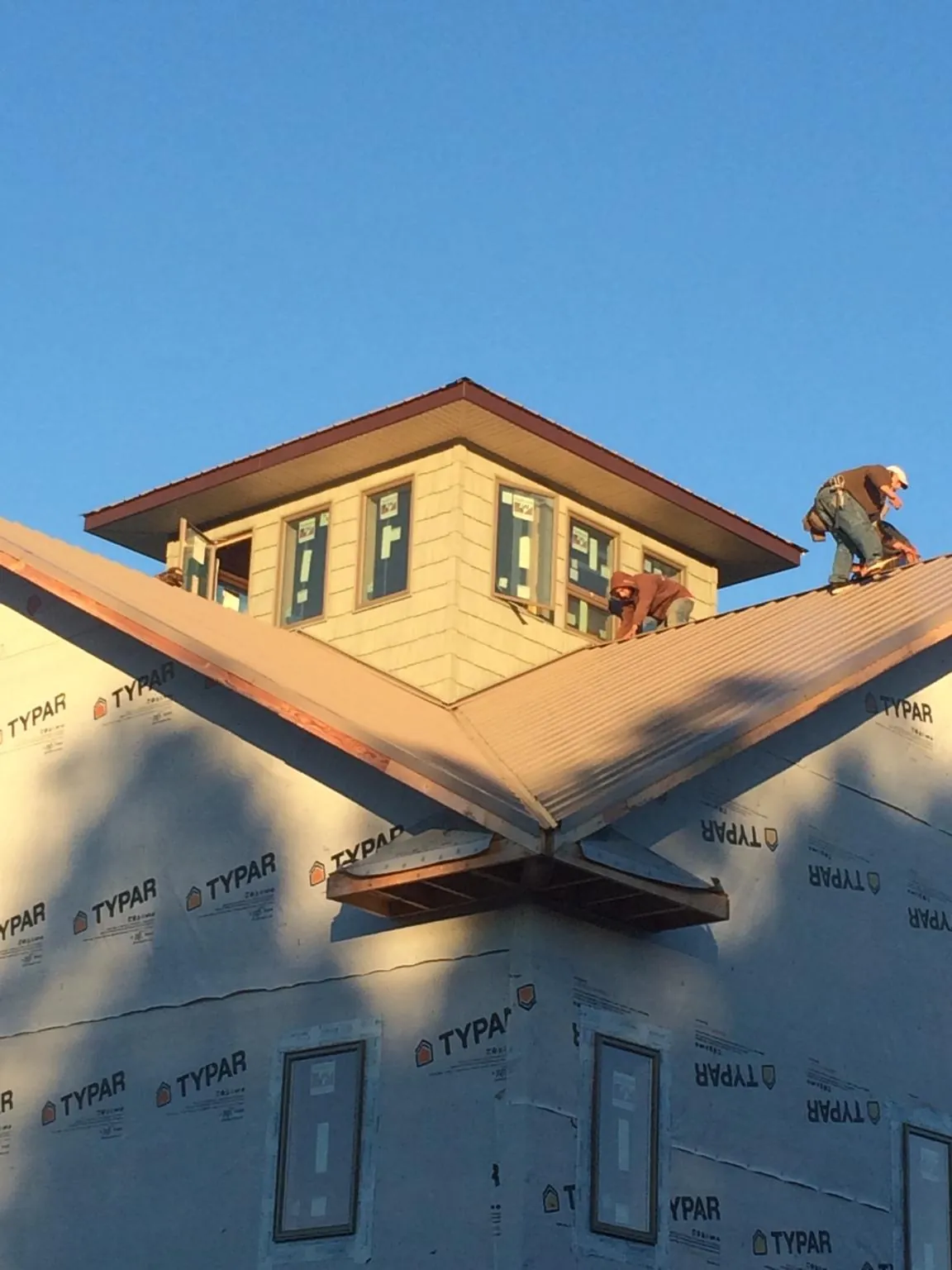 Roofers working around a rooftop cupola on a new metal roof at sunset — Roof Waterproofing in Palmetto by Roofing Brothers
